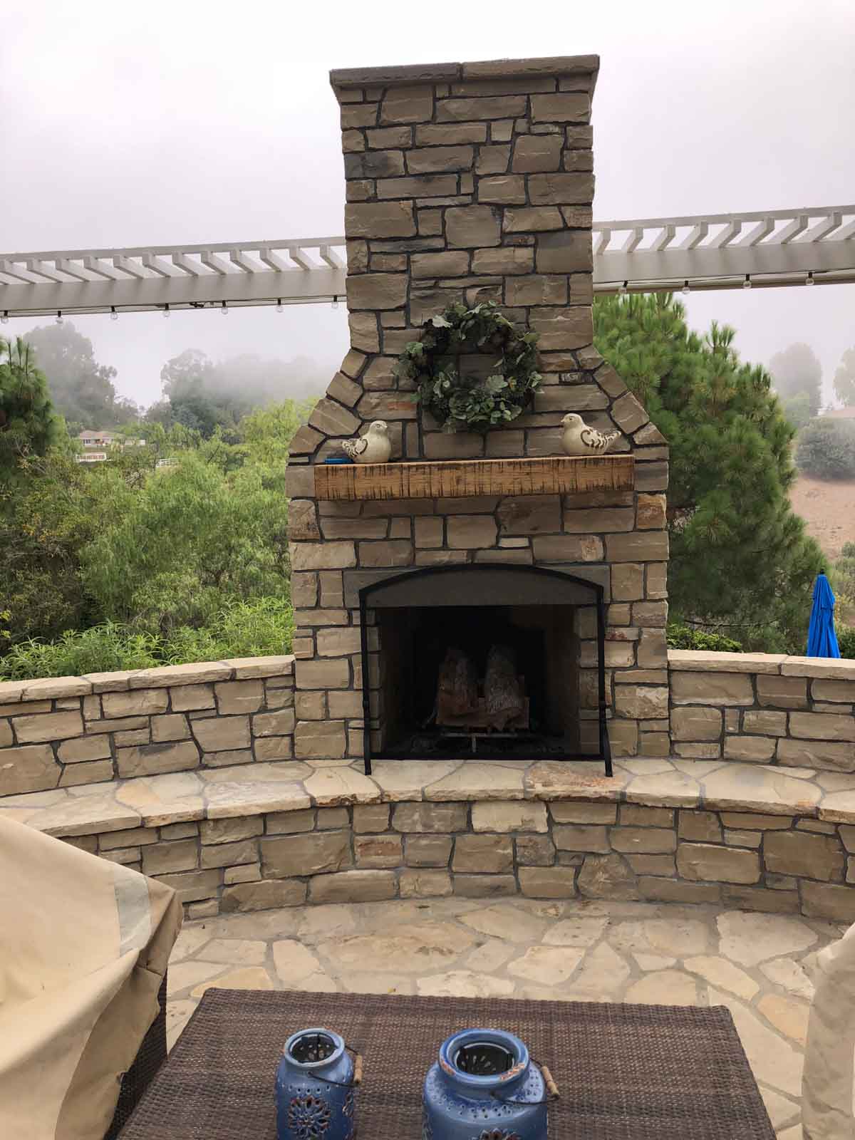 Full-height outdoor stone fireplace anchoring a patio seating area
