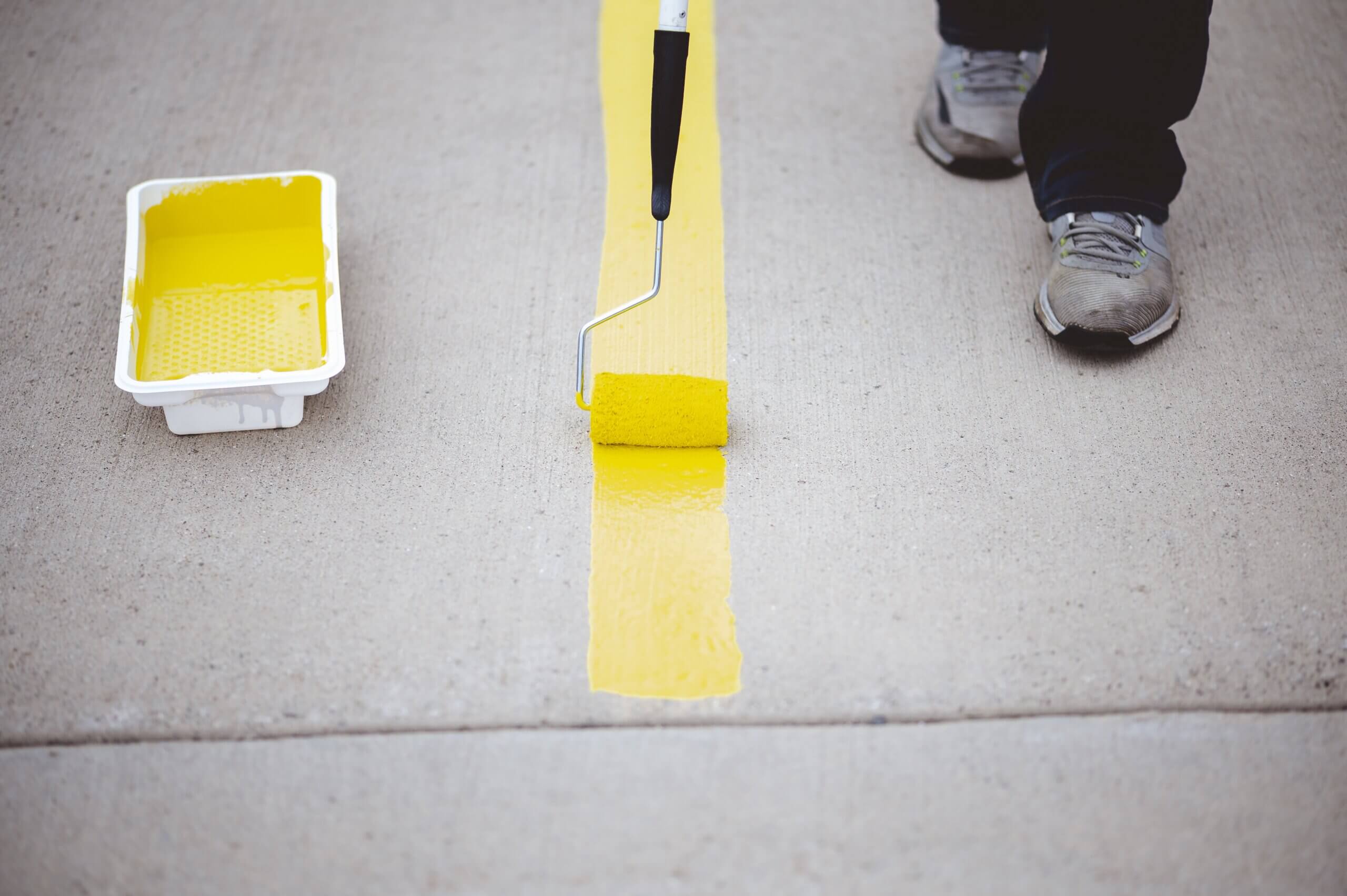 Worker repainting lines on a paved surface