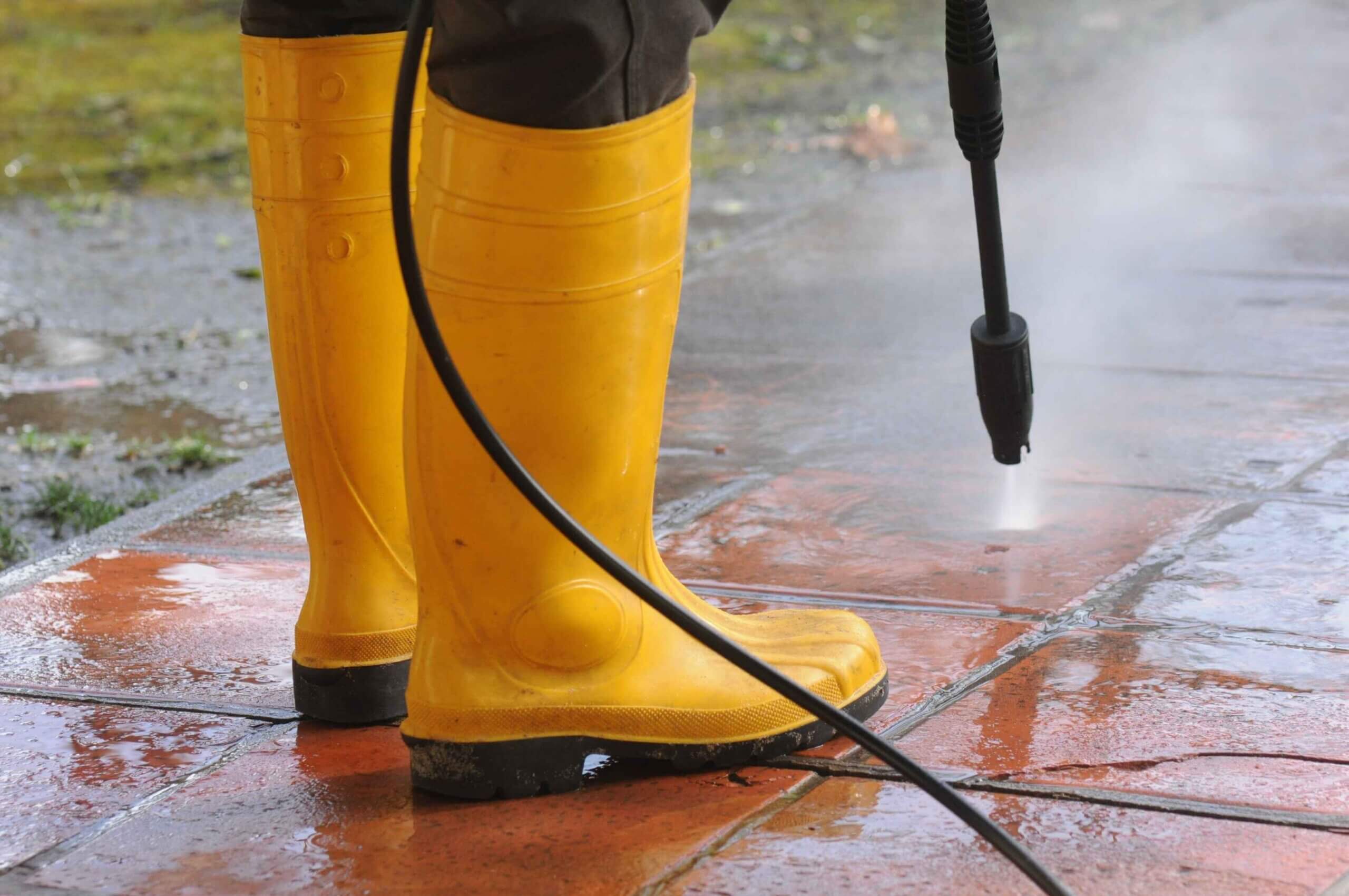 Person pressure washing dirt off tiles