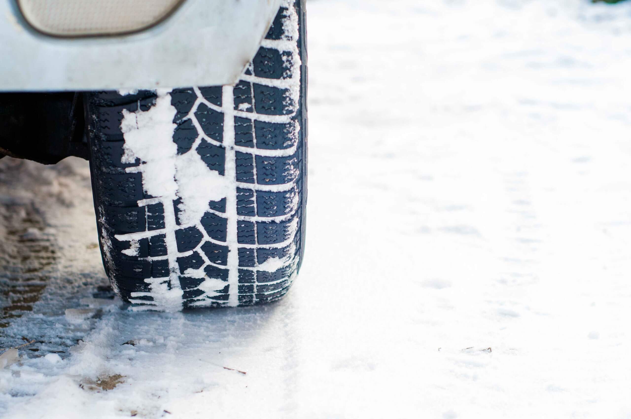 Car tires on a snowy road covered in snowfall