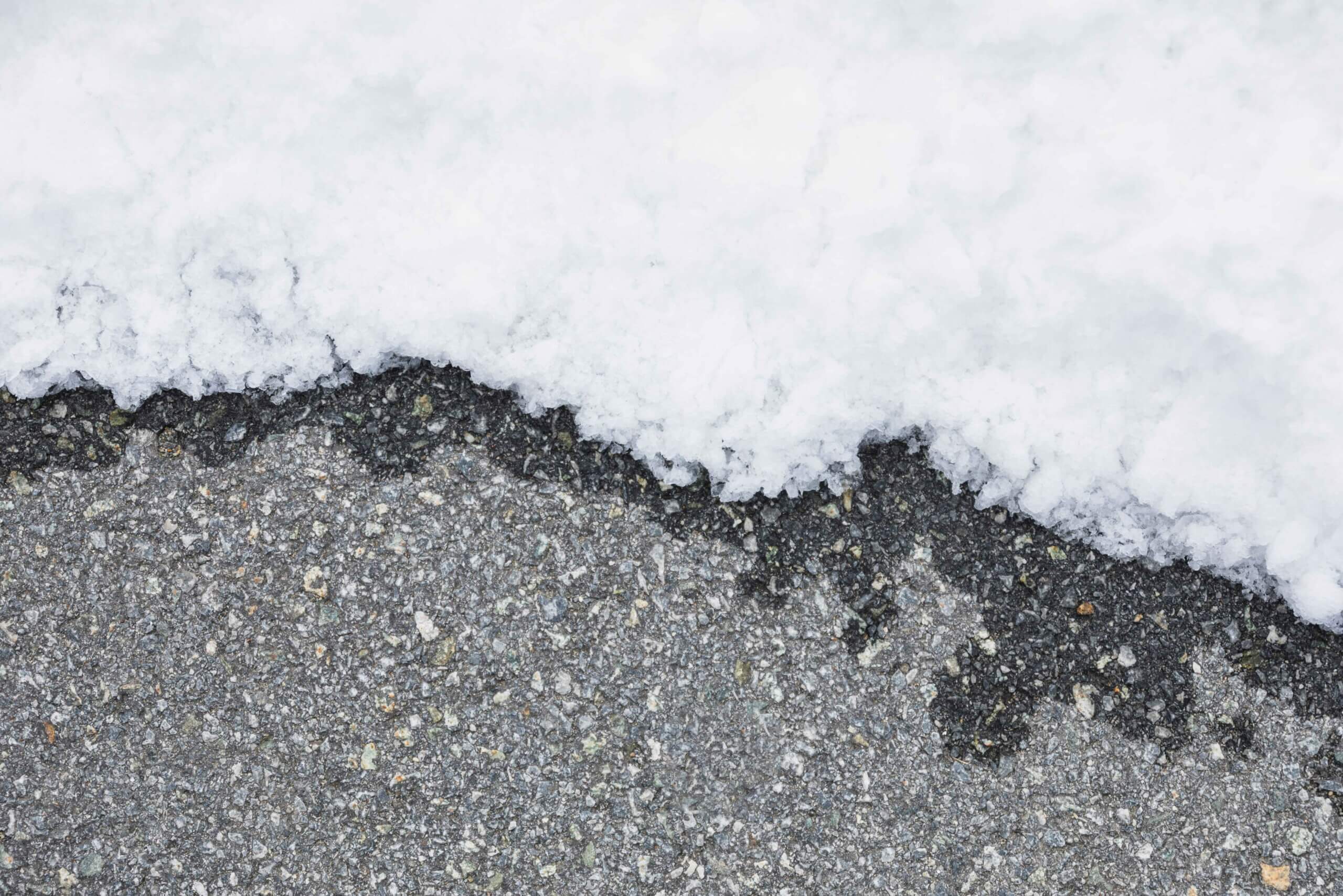 Wet asphalt driveway near melting snow
