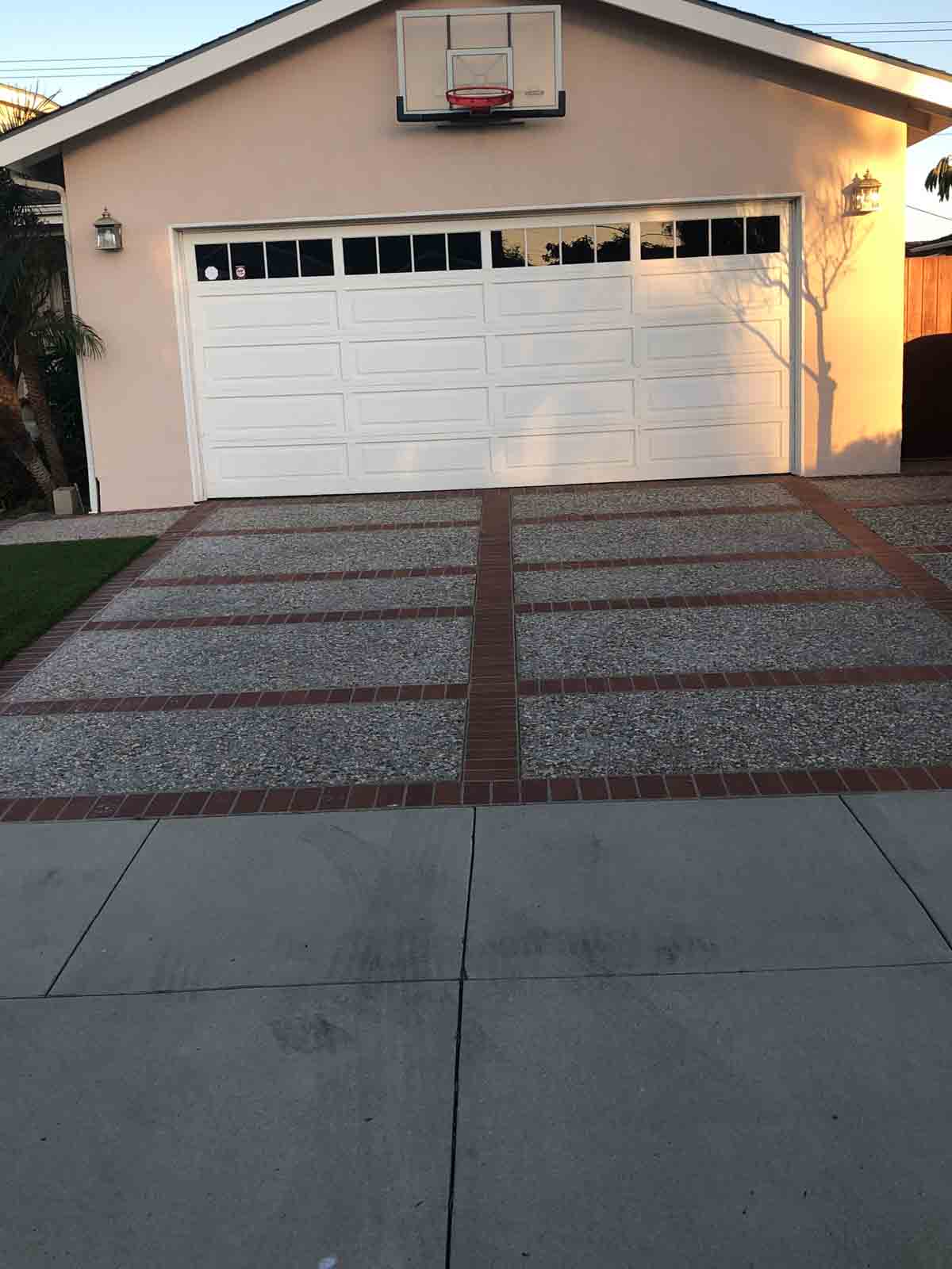 Exposed aggregate driveway with red brick banding in front of a garage