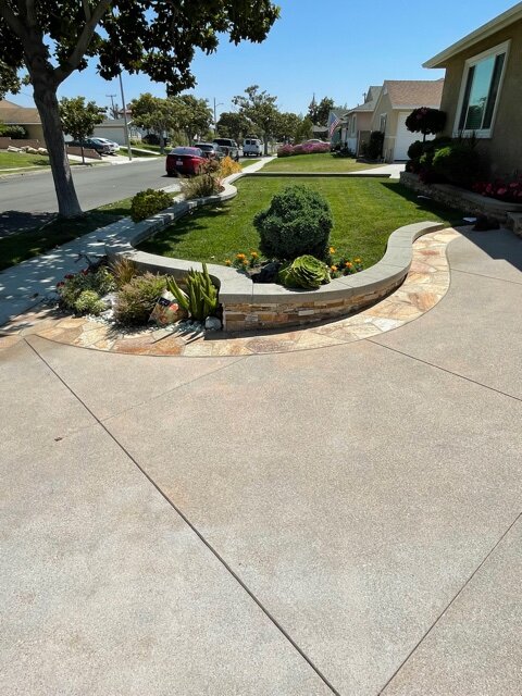 Curved concrete driveway alongside a stone-capped garden wall