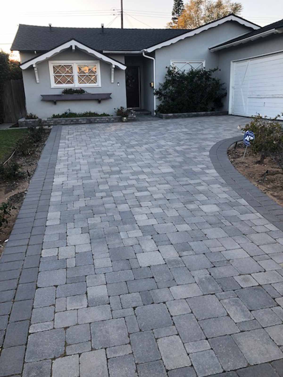 Curved gray cobble paver driveway sweeping up to a garage