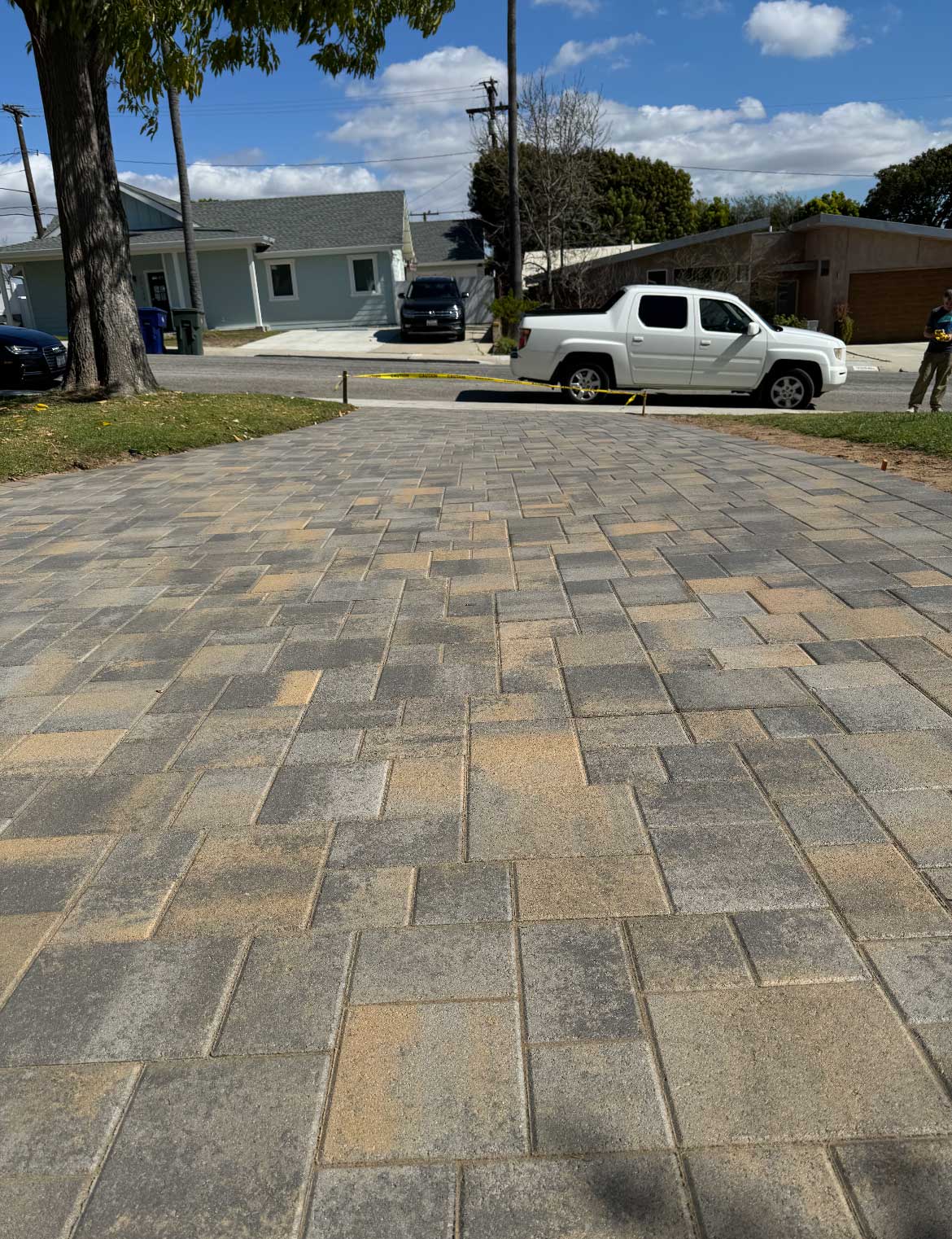 Wide interlocking paver driveway in mixed earth tones leading to the street
