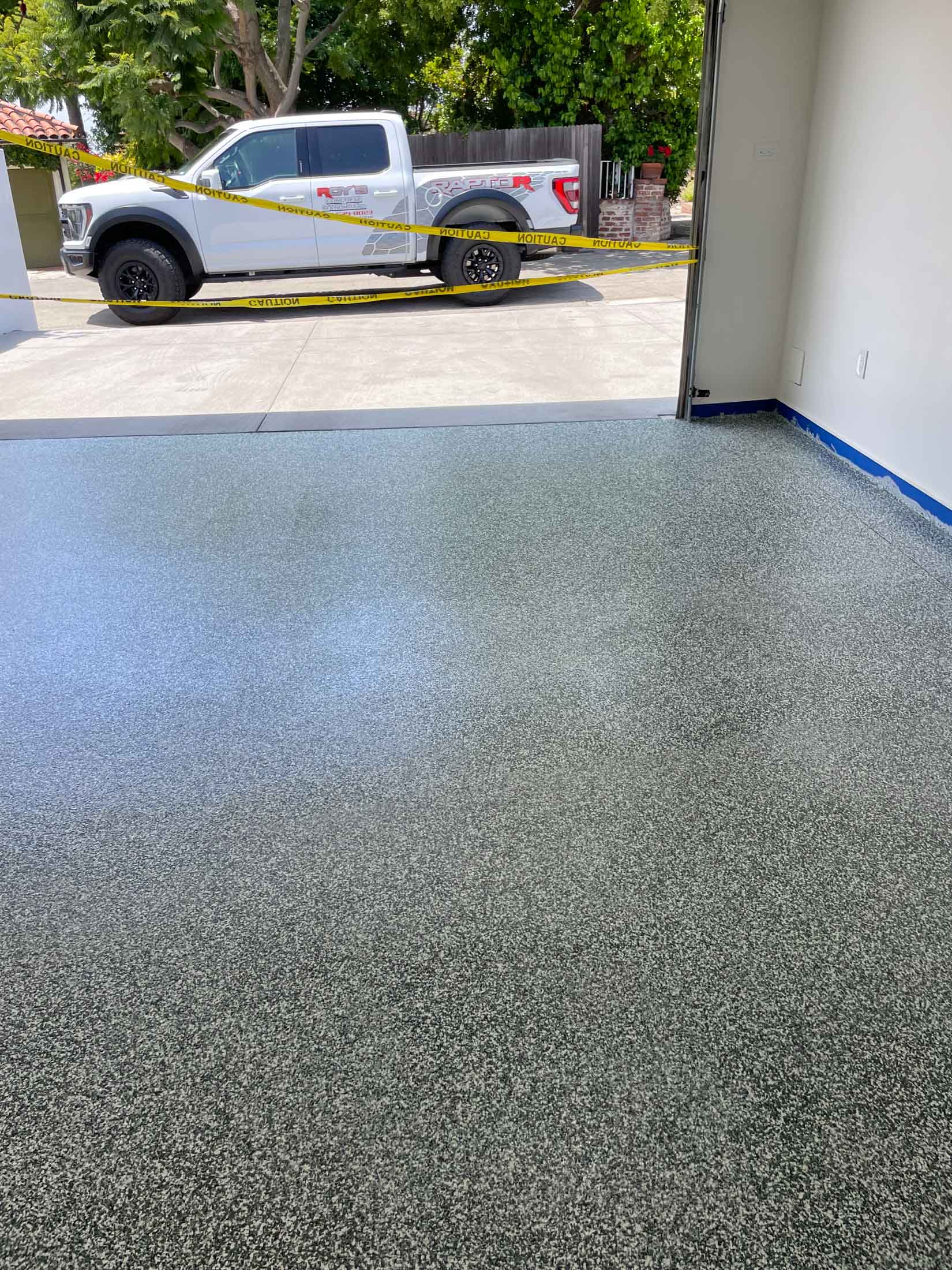Garage with a fresh gray flake epoxy floor, door open to the driveway