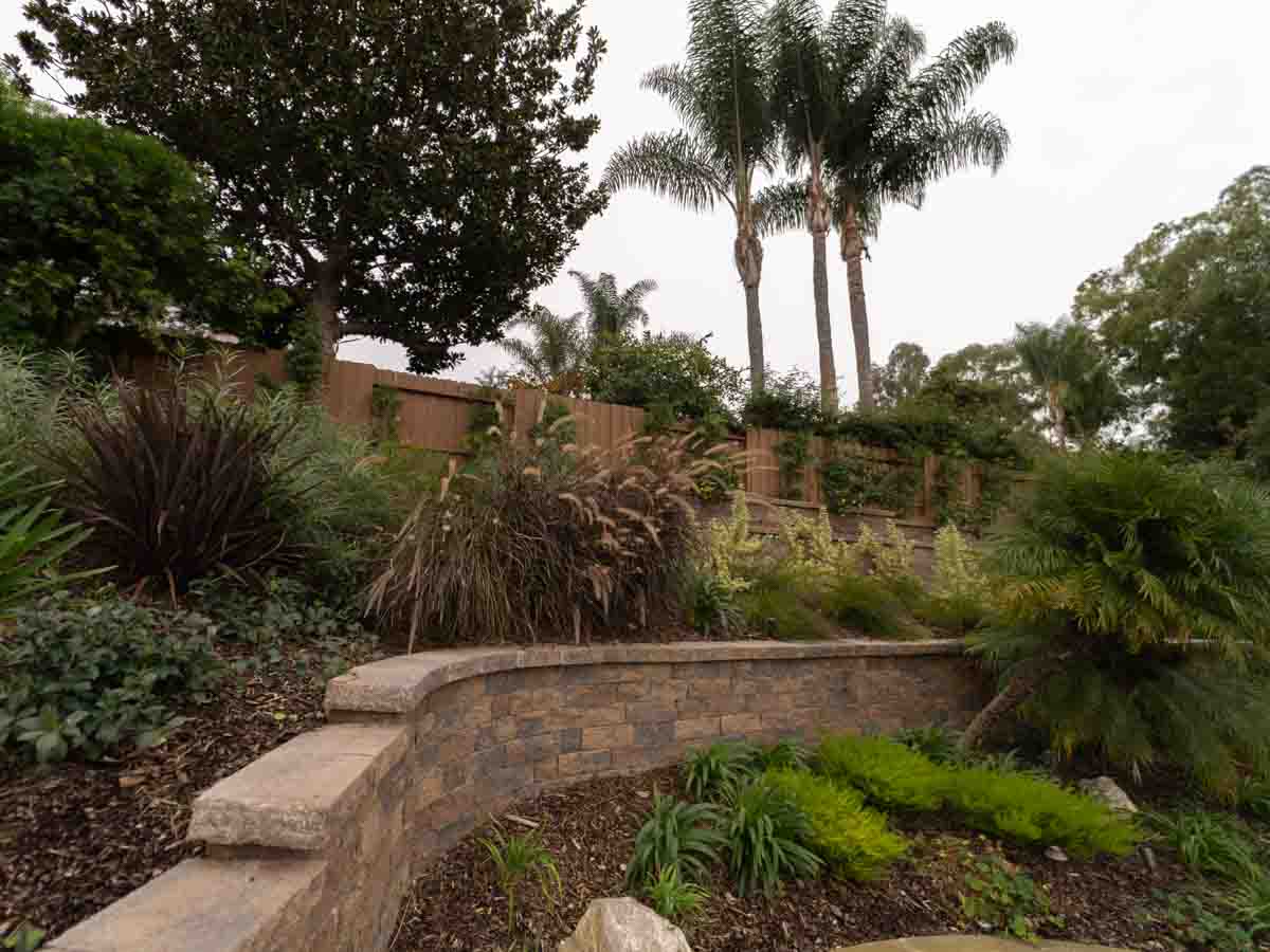 Curved block garden wall with cap stones holding a planted hillside
