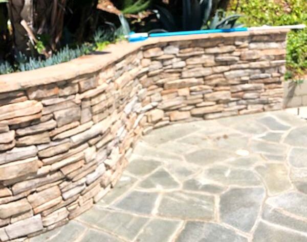 Curved stacked stone wall wrapping a spa area with agave plants