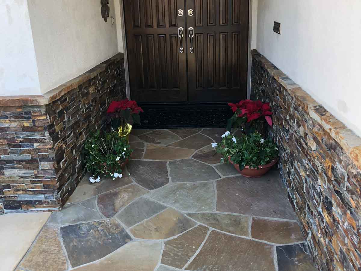 Flagstone entry landing at a front door with stacked stone wainscot on the walls