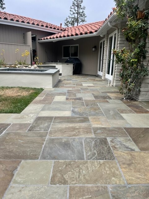 Multicolor natural stone patio laid off the back of a house