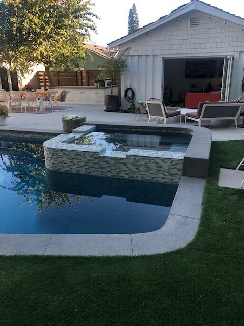 Backyard spa with glass tile and a paver deck