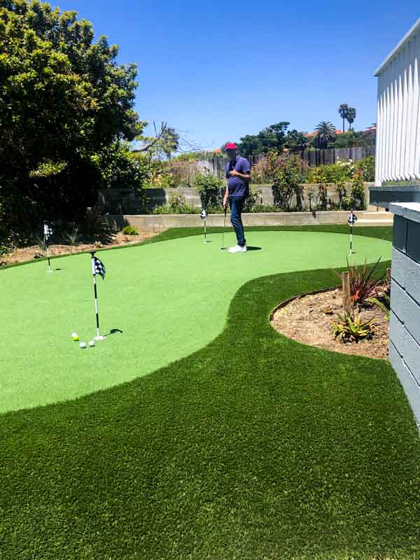 Man putting on a backyard green that curves around a planted bed