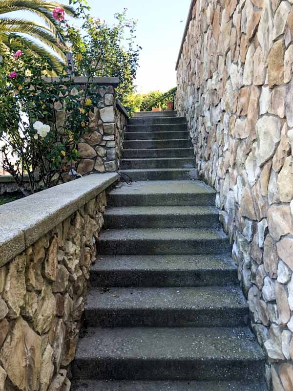 Hillside concrete stairway flanked by natural fieldstone veneer walls