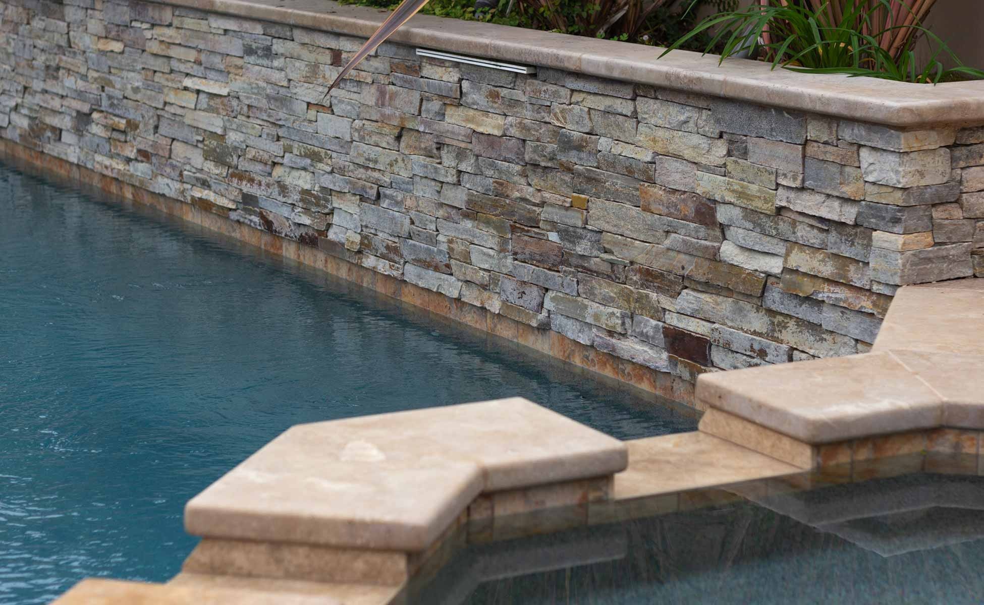 Backyard with terraced ledger stone retaining walls, pool, and raised spa