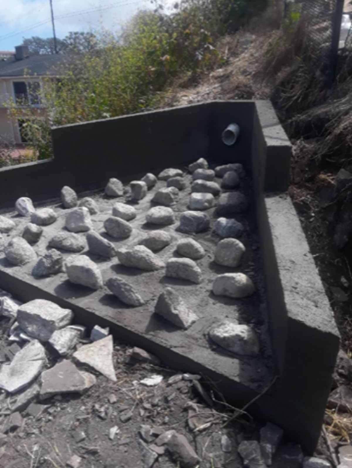 Grouted riprap stones set in a concrete drainage basin
